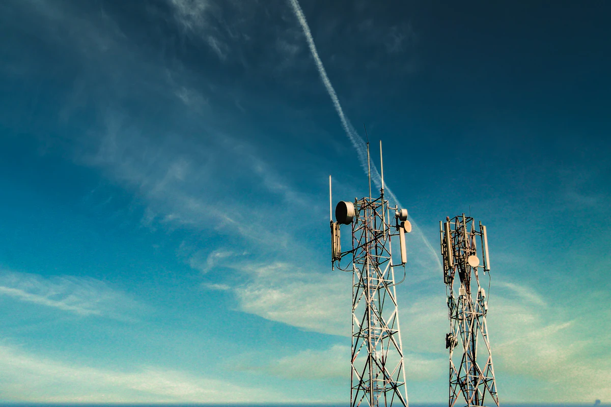 Cell towers with mounted antennas against a blue sky